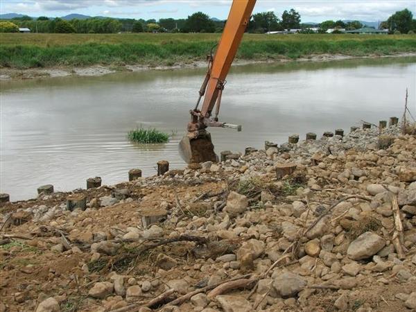 Stream rock placed around piles to form extra river berm